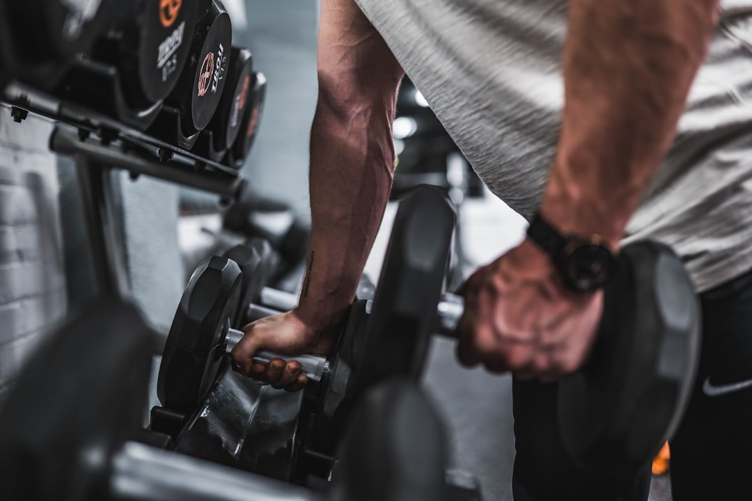 A person performing a strength training exercise with dumbbells in a home gym setting.